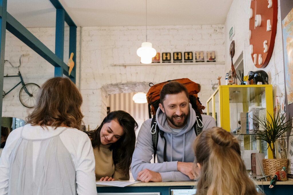 pexels photo 5137954 5137954 Backpackers cheerfully checking in at a vibrant hostel reception desk.